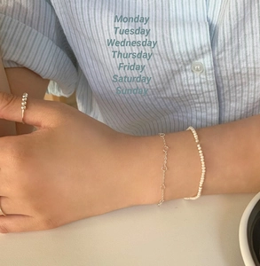 Detail showing layered silver knot chain bracelet and dainty pearl jewelry set on wrist