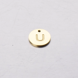 Macro detail of a 12mm round gold stainless steel pendant featuring the letter U engraving