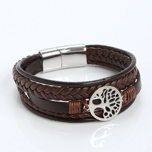 Macro detail of brown braided leather bracelet with silver tree of life charm and magnetic clasp