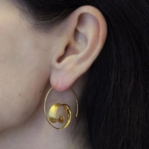Boucles d'oreilles créoles spirales dorées à texture métallique brossée sur mannequin