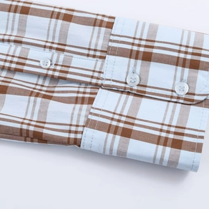 Macro view of blue plaid poplin shirt cuffs featuring clear texture and white buttons