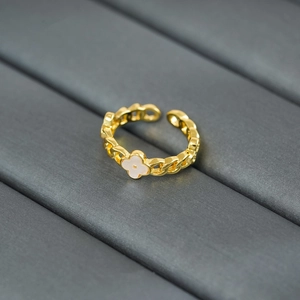Detailed macro of gold chain ring featuring a white shell four-leaf clover floral motif
