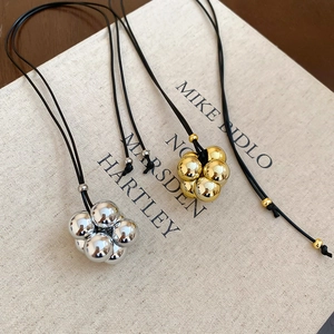 Dettaglio di pendenti geometrici in oro e argento su cordino nero minimalista