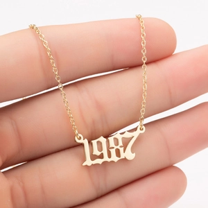 Macro view of gold stainless steel necklace with 1987 birth year pendant in retro font