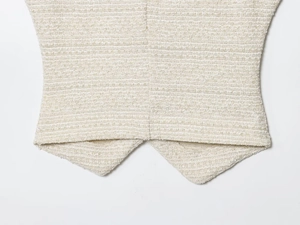 Détail du tissu en tweed crème montrant l'ourlet tissé de haute qualité du gilet et du pantalon