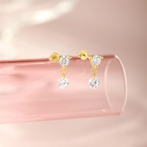 Detail of S925 sterling silver gold-plated earrings with swinging white zircons