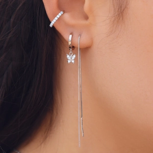 Detail of silver S925 earrings with sparkling butterfly pendant and long chain tassel