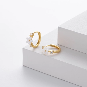 Detailed view of gold flower earrings with white petals and sparkling zircon stones