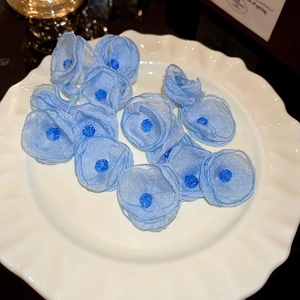 Détails de boucles d'oreilles fleurs en tulle bleu et perles sur plat en dentelle
