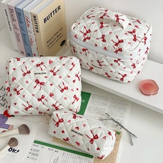 Three-piece set of white quilted cosmetic bags with red bow and heart patterns in various sizes