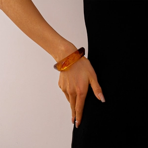 Close-up of translucent amber acrylic bangle with smoky marble texture on wrist