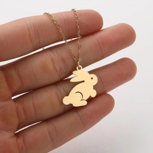Macro view of a gold rabbit pendant necklace held in hand showing fine metal details