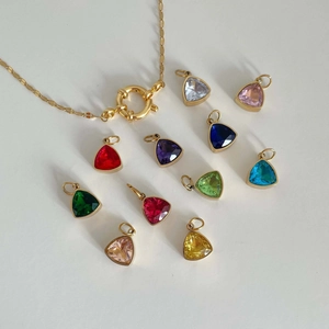 Close-up of golden chain necklace with ten colorful triangle crystal pendants on white background