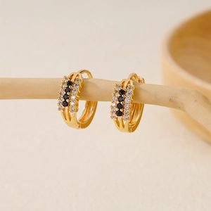 Detailed macro shot of gold hoop earrings with black and white pavé-set zircon stones