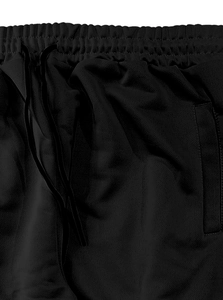 Dettaglio dei pantaloni sportivi neri con vita elastica, coulisse e trama in mesh