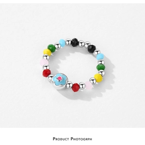 Dettaglio anello fiore in argento S925 con perline multicolore su sfondo bianco pulito