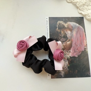 Handmade black scrunchie with pink fabric roses and ribbon bows on a vintage background