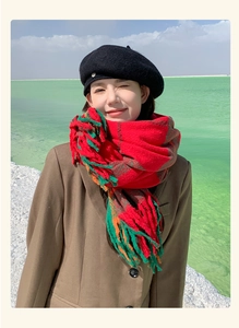 Close-up of a red and green plaid scarf with tassels on a model at a scenic lake