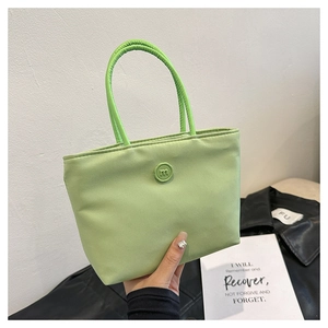 Detail van avocado groene nylon emmertas met dubbele handvaten en rond m-letter embleem