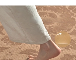Detail of soft vintage floral rug texture with a foot showing plush thickness and support