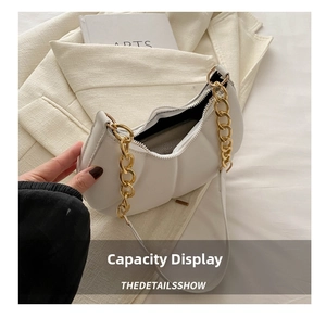 Close-up of white pleated crescent bag with gold chain strap and smooth zipper detail
