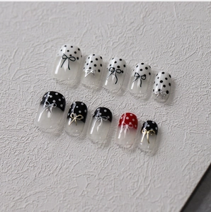 Detail of minimalist bow nail stickers with black dots and 3D metallic bow accents