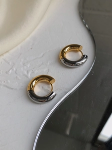Macro shot of two-tone gold and silver chunky hoop earrings with a high-polished finish