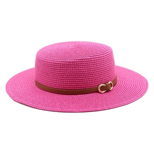 Détail d'un chapeau de soleil rose avec bande en cuir marron et boucle dorée en mors