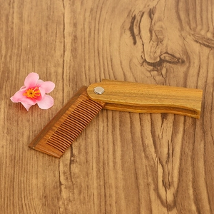 Foldable green sandalwood beard comb with natural wood grain on a wooden surface