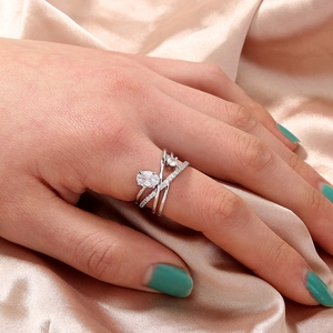 Close-up of interlocking silver ring with pavé zircons worn on hand over champagne silk