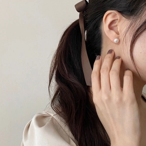 Elegant woman wearing 925 silver pearl earrings and a brown silk bow headband accessory