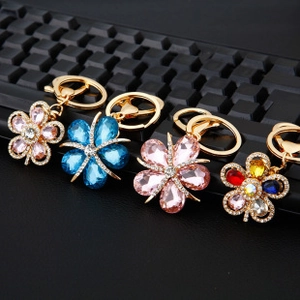 Detail of four floral crystal keychains in pink and blue on a textured surface