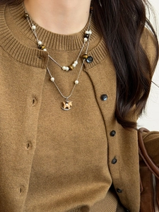 Detail of double-layered pearl necklace with tiger eye beads and wooden horse pendant