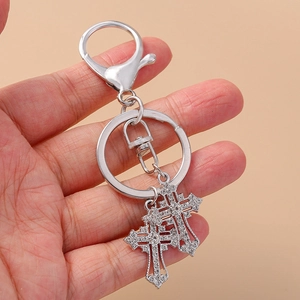 Silver gothic cross keychain with rhinestones and star charms held in hand closeup