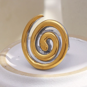 Detail shot of the two-tone gold and silver spiral design ring on a ceramic base