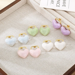 Five pairs of heart-shaped resin earrings in pastel colors on a beige display tray