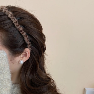 Detailansicht eines Samt-Haarreifs mit Leopardenmuster und eleganter Perlenohrring