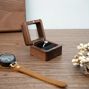 Close-up of portable walnut wood ring box with black velvet lining on vintage wooden desk