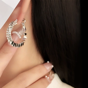 Silver-plated C-shaped earrings with rhinestones and black oval accent on female model