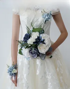 Détail du bouquet de mariée et du corsage avec des roses blanches et des fleurs bleu morandi