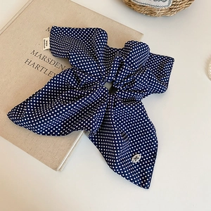 Detail of dark blue polka dot hair scrunchie with streamers and handmade label