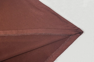 Detail view of double-stitched hem and satin fabric texture on the brown dress