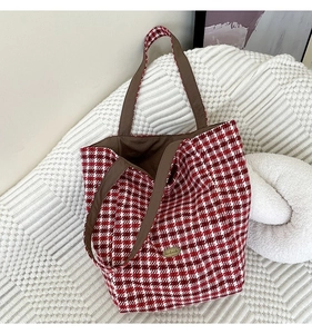 Close-up of red and white checkered wool tote bag with handmade metal logo detail