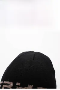 Dettaglio del berretto in maglia nera con motivo jacquard marrone e trama intrecciata
