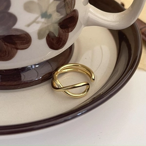 Detailed view of a gold minimalist twisted double-layer ring on a ceramic cup edge