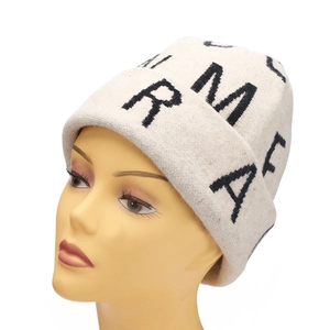 Close-up of cream knit beanie with black jacquard letters and wide folded cuff detail