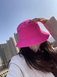 Detail of a bright pink cotton bucket hat with breathable eyelets worn by a model outdoors