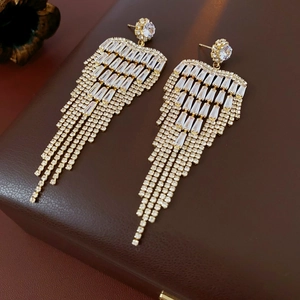 Detail of long gold tassel earrings with rectangular and round sparkling zircons