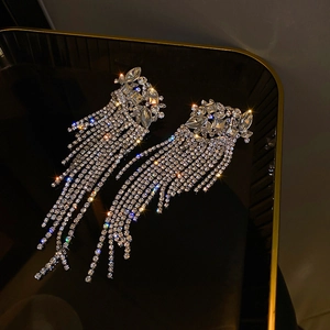Macro shot of silver tassel earrings with sparkling rhinestones on black display tray