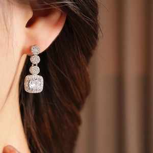 Detail shot of a silver square zircon drop earring with crystals on a model's ear